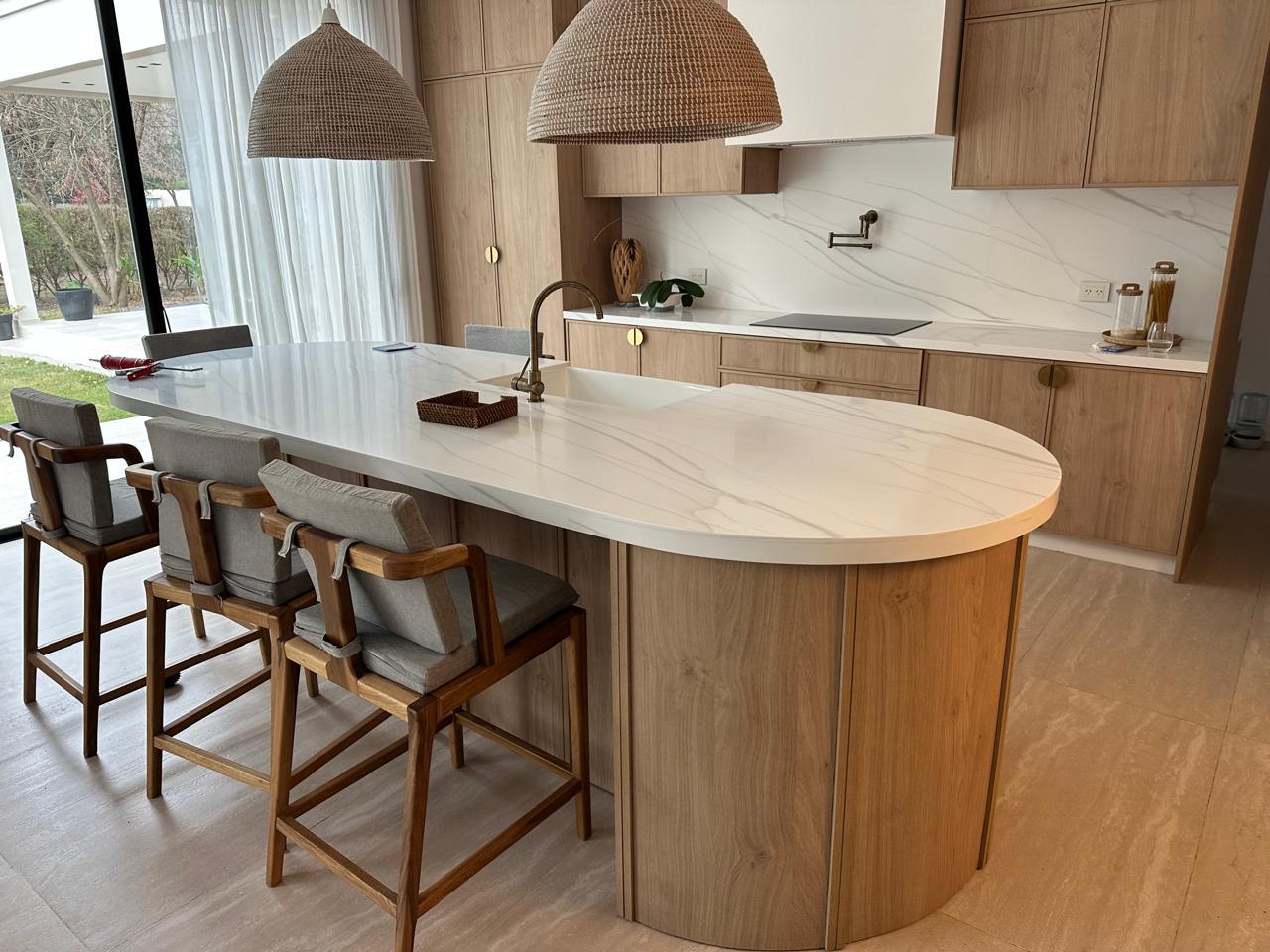 Isla de cocina curva con mesada blanca realizada a medida