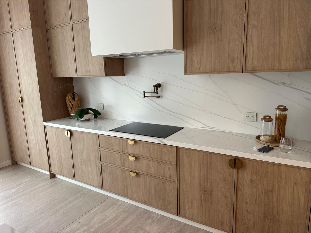 Mesada y alzada blanca en cocina con mobiliario de madera